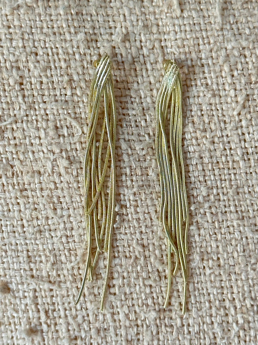 Pendientes flecos cadenas snake doradas sostenidos en mano, vista frontal