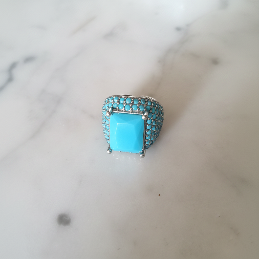 Anillo Yasmine turquesa con circonitas sobre mármol, vista lateral